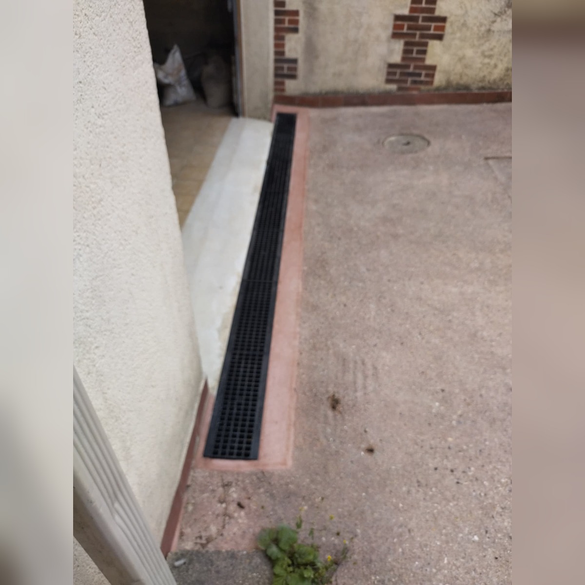 Caniveau de drainage en pied de façade le long d'une cour bétonnée